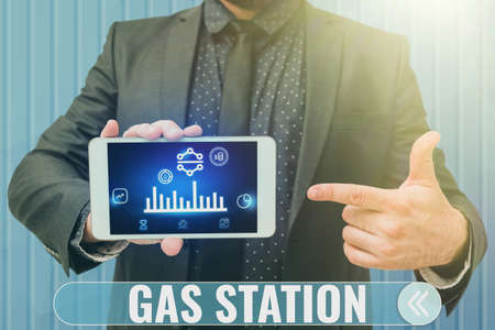 Hand writing sign Gas Station. Business idea for servicing motor vehicles especially with gasoline and oil Man holding Screen Of Mobile Phone Showing The Futuristic Technology.の写真素材