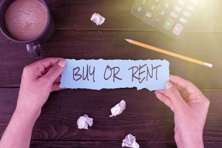 Handwriting text Buy Or Rent. Word Written on Doubt between owning something get it for rented Indecision Woman Hands Holding Blank Paper And Stationery Over Wooden Table.の写真素材