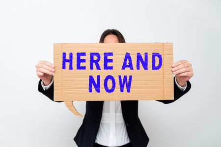 Writing displaying text Here And Now. Concept meaning Present at this exact moment Compromise Engagement in situation Businessman in suit holding open palm symbolizing successful teamwork.の写真素材