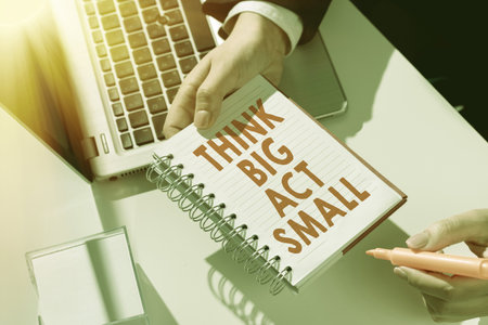 Text sign showing Think Big Act Small. Conceptual photo Great Ambitious Goals Take Little Steps one at a timeの写真素材