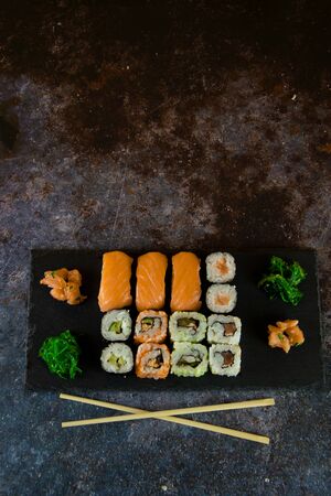 Set of sashimi sushi and sushi rolls served on stone slate. And accompanied with traditional soy sauce and seaweedの写真素材