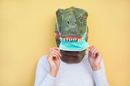 Crazy woman wearing t-rex and medical protection masks - Quarantine isolation lifestyle during coronavirus time - Absurd and funny trend concept - Focus on noseの写真素材