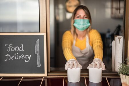 Young woman preparing delivery food inside takeaway restaurant during Coronavirus outbreak period - Worker inside kitchen cooking healthy food for home order service - Focus on handsの写真素材