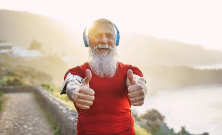 Happy senior man with thumbs up after workout session - Mature athlete doing jogging outside while...