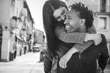African couple having fun outdoor in city tour - Young people lovers enjoying time together - Love, fashion, travel and relationship concept - Focus on man face - Black and white editingの写真素材