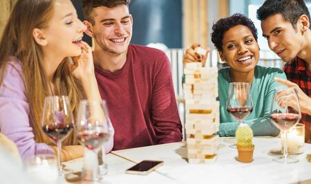 Young friends playing board games at home - Happy people having fun doing party in living room house at evening time - Fest during isolation quarantine - Focus on african girl faceの写真素材
