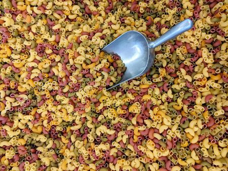 Colorful maccheroni tricolori pasta with a large metal spoon in a zero waste store or supermarket in a new environmentally friendly trend of unpackaged food.の写真素材