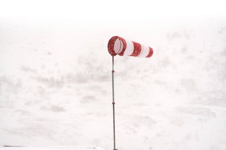 Windsock in a snow storm fluttering in the wind isolated against the white background of snowy...