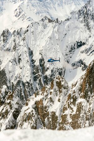 Helicopter flying in a valley between high mountains and rocky walls
