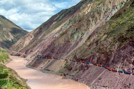 Line of trucks stuck in a traffic jam in an impossibly narrow and dangerous mountain road over a...