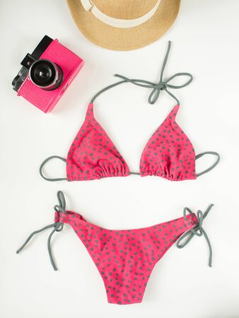 Summer outfit, beach outfit, summer stuff. Pink polka dot swimsuit, retro camera, straw hat. Flat lay, top viewの写真素材