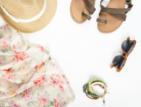 Summer outfit. Summer background. Flower dress, straw hat, sandals, brown sunglasses, bracelet. Flat lay, top view, round view.の写真素材