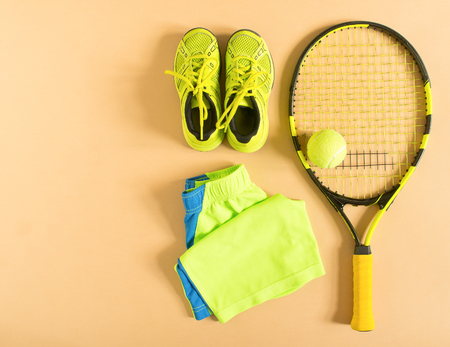 Tennis stuff on cream background. Sport, fitness, tennis, healthy lifestyle, sport stuff. Tennis racket, lime trainers, tennis balls, lime athletic shorts. Flat lay, top view.の写真素材