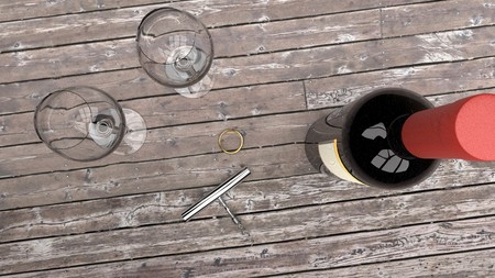 Romantic date and prepartion for a marriage proposal - expensive gold ring, bottle of red wine, two wine glasses and an opener on a dark wooden tableの写真素材