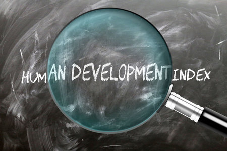 Learn, study and inspect Human Development Index. A magnifying glass enlarging word 'human development index' written on a blackboardの写真素材