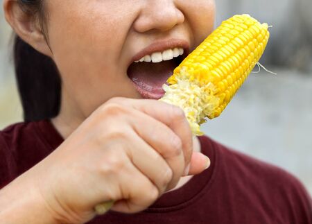 Girl eating boiled sweet corn, close-up photos.の写真素材
