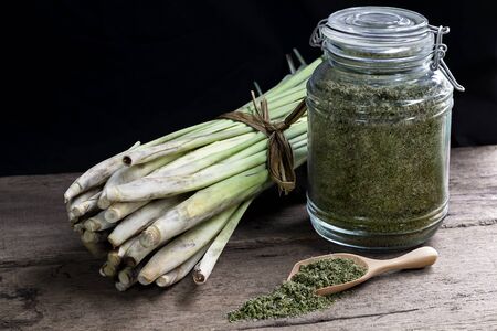 Lemon Grass (Cymbopogon citratus) and Dried lemongrass in glass bottles on wood table.の写真素材