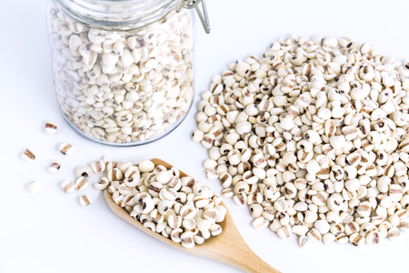 A pile Job's tears or Coix lacryma-jobi isolated on white table background. Job's tears in the wooden spoon and in the glass bottle. Concept food for healthy.の写真素材