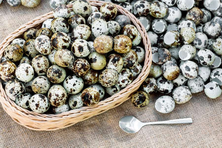 Quail eggs a lot of in basket and heap shell quail eggs on sackcloth of the wooden background.