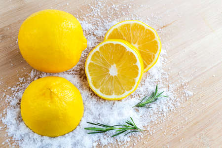 Lemon and sea salt - Beauty treatment with organic cosmetics with lemon ingredients on wood and rosemary background for body scrub and spa care.の写真素材
