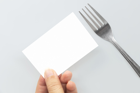 Blank paper mock up card and hand holding of fork. Creative layout for business food concept. With clipping path.の写真素材