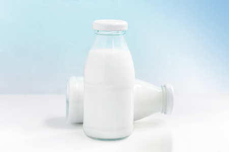 Two glass bottle of milk on the white table on a blue background. with copy space for text.の写真素材
