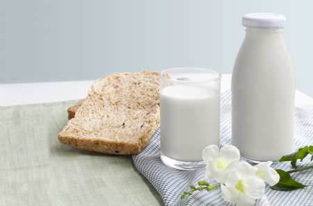 A bottle of milk and glass of milk with sliced bread on blue and green cloth isolated on white table background for food and healthy concept. with copy space for text.の写真素材