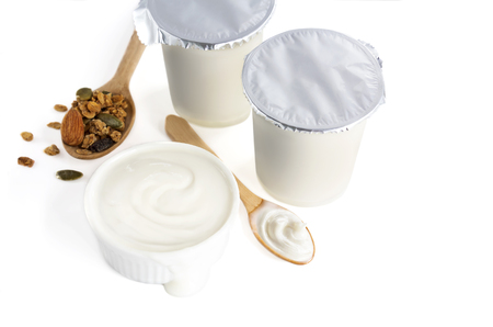 Healthy flavored yogurt in plastic cup and ceramic bowl with cereal and wooden spoon isolated on the white background. With copy space for your text.の写真素材