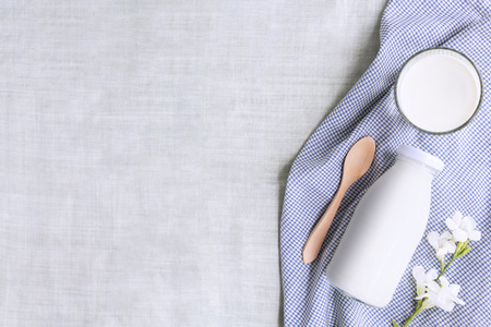 A bottle of milk and glass of milk with wooden spoon and white flower on blue cloth isolated on green background for food and healthy concept. with copy space for text.の写真素材