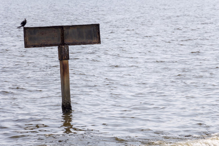 Blank Sign board iron on pole in the sea with reflection light in rippled effect textured water for design backgrounds and textures concept. With copy space for text.の写真素材