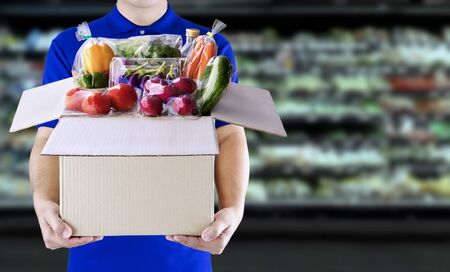 Food delivery service for order online grocery shopping concept. Delivery man in blue uniform hand holding paper box package. Express delivery service fast food for lifestyle in city concept.の写真素材