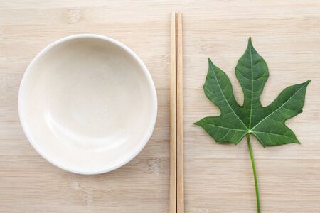 Ceramic plate with chopsticks mock up on wooden table background with copy space for text. Creative layout with food concept.の写真素材