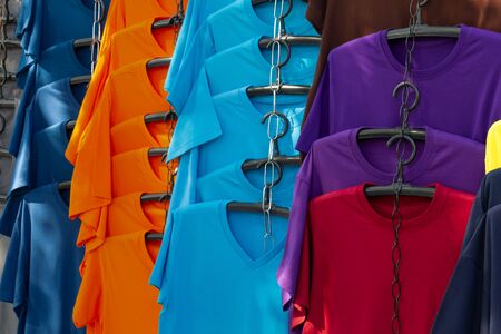 Colorful clothes with fashion clothing hang on hanger in a designer store or shopping mall for sale. Business clothes t-shirt concept.の写真素材