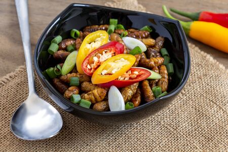 Silkworm Pupae (Bombyx Mori). Food insects for eating as food items made of cooked insect meat with seasoning in bowl and spoon on sackcloth is good source of protein edible. Entomophagy concept.の写真素材
