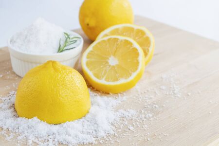 Lemon and sea salt - Beauty treatment with organic cosmetics with lemon ingredients on wood and rosemary background for body scrub and spa care.の写真素材