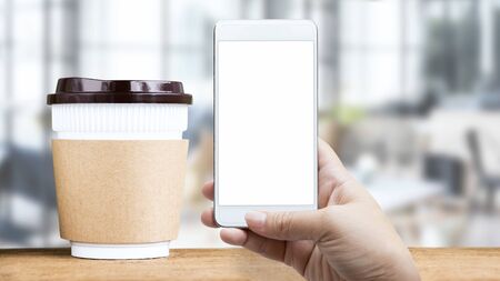 Online order food shopping and delivery service on touch screen. Woman hand holding smart phone scanning on disposable cup for payment in coffee shop. Business digital and technology concept.の写真素材