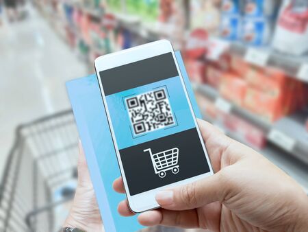 Online order grocery shopping on touch screen concept. Woman hand holding smart phone and scanning QR code for ordering ingredients food which delivery service at home for cooking.の写真素材