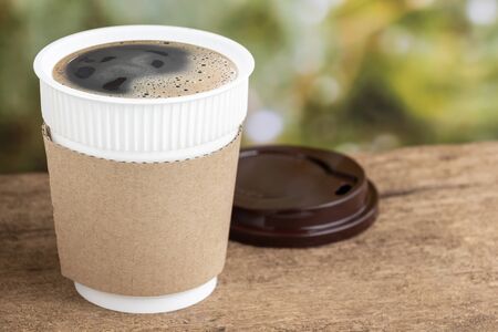 Coffee cup or disposable cup on the wooden table background on natural morning with copy space for your text and logo.の写真素材