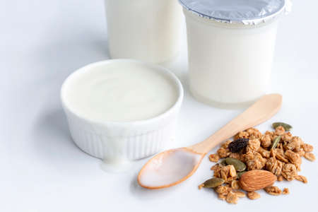 Healthy flavored yogurt in plastic cup and ceramic bowl with granola on white background for organic food healthy with copy space for text.の写真素材