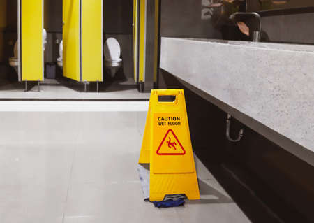 Sign yellow slippery warning floor wet, caution for toilet room cleaning progress. Safety sign with...