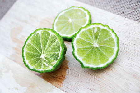 Bergamot fruit cutting slices on wooden clipping board on sackcloth background. Bergamot material of...