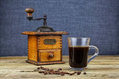 Black coffee in a glass and an old grinderの写真素材