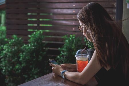 Women are sitting drinking fruit juice and using a smartphone.のeditorial素材