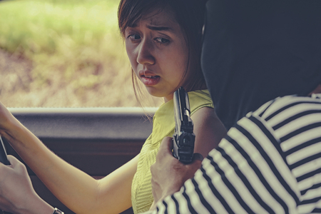 Thief robbery pointing gun to woman in car, bad man concept.の写真素材