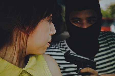Bandit robbery woman with gun in car ,Dangerous criminal of women in the city.の写真素材