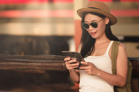 portrait asian girl looking for travel information by tablet traveler by the train.