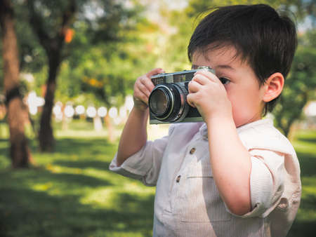 little kids boy taking a picture using a vintage retro film in nature parkの写真素材