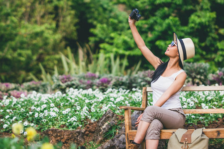 young girl taking photo flower in garden journey backpack.の写真素材