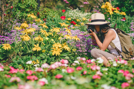 young girl taking photo flower in garden journey backpack.の写真素材