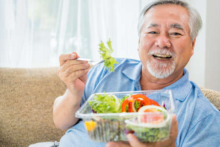 Happy old man positive, Portrait Asian Senior man and eyeglasses using computer laptop in bedroom at home, Old elderly male Technology communication retirement lifestyles concept.の写真素材